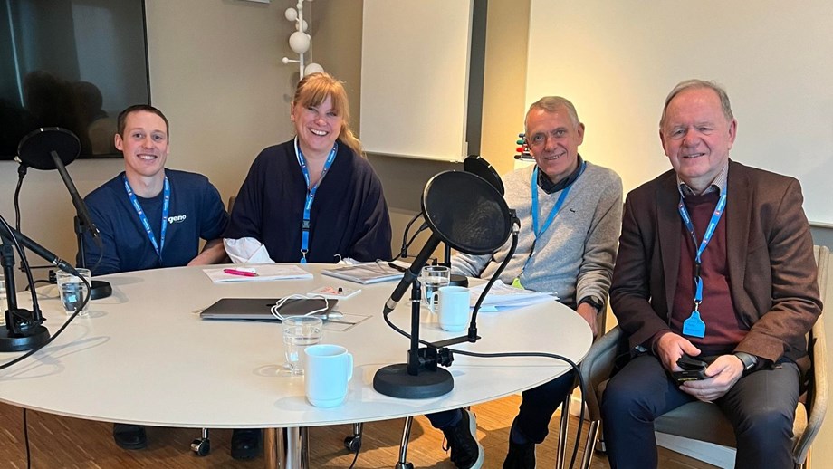 Programlederne og gjester sitter rundt et bord med mikrofon i Genopodden sitt studio