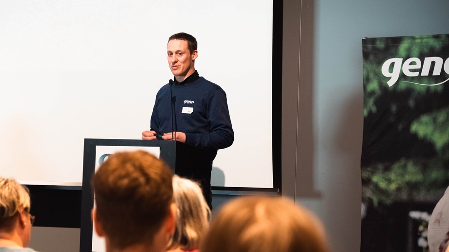 Styreleder Vegard Smenes står ved talestolen med et hvitt lerret bak seg og noen bakhoder fra forsamlingen i forgrunnen. Foto: Turi Nordengen.