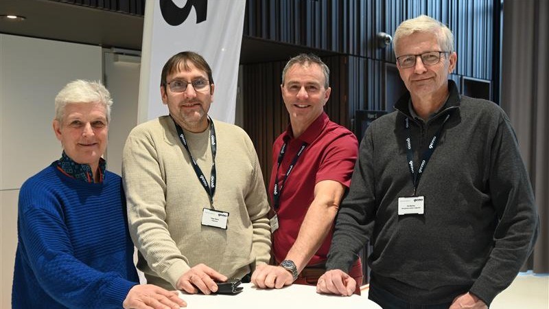 Valgkomiteens medlemmer står oppstilt foran et lite rundt bord og ser mot fotografen.