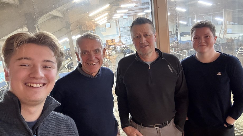 Selfie av programledere og gjester hvor de står oppstilt ved siden av hverandre. I bakgrunnen er det vindusruter med utsyn ned i fjøset.