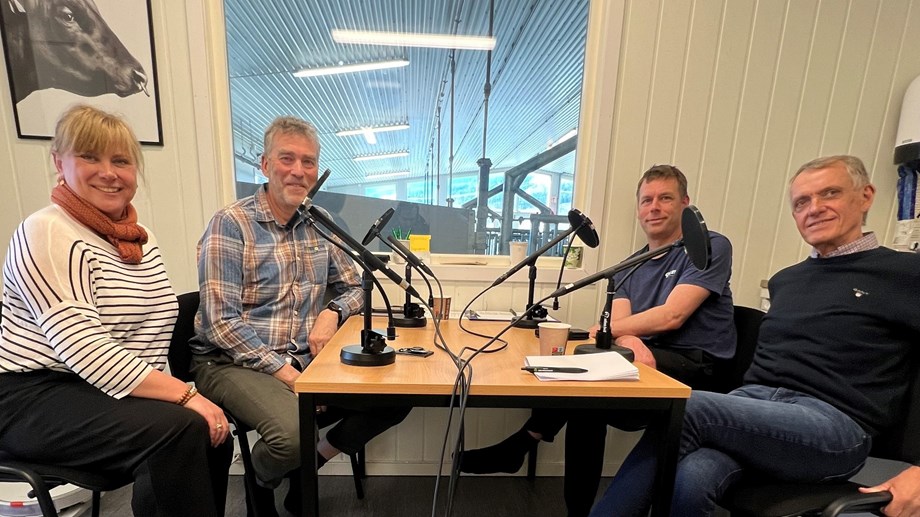 Programlederne og to gjester sitter rundt et bord med mikrofoner. Et vindu ut mot fjøset i bakgrunnen.
