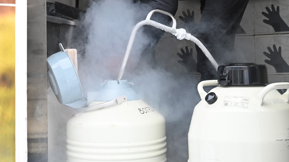 To beholdere med en slange mellom hvor nitrogen fylles i den ene som står med åpent lokk.