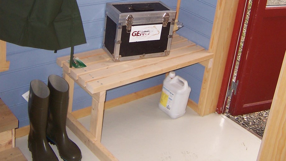 Bilde av smittesluse med benk til inseminasjonskoffert, støvler og veterinærfrakk.