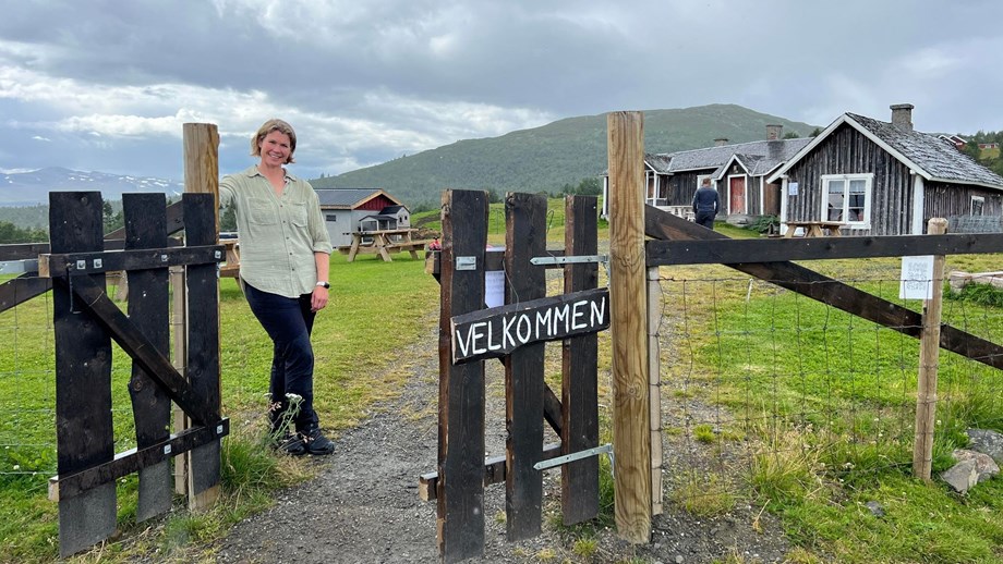 Bilde av produsent Lena Lisjordet som står i porten inn til stølen Lisjordet i Valdres