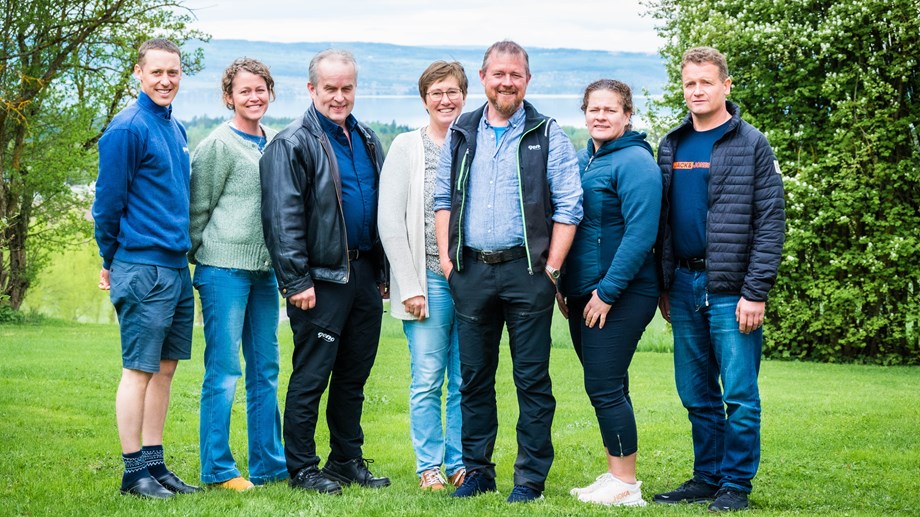 Styremedlemmene står oppstilt sammen på en plen med trær i bakgrunnen.