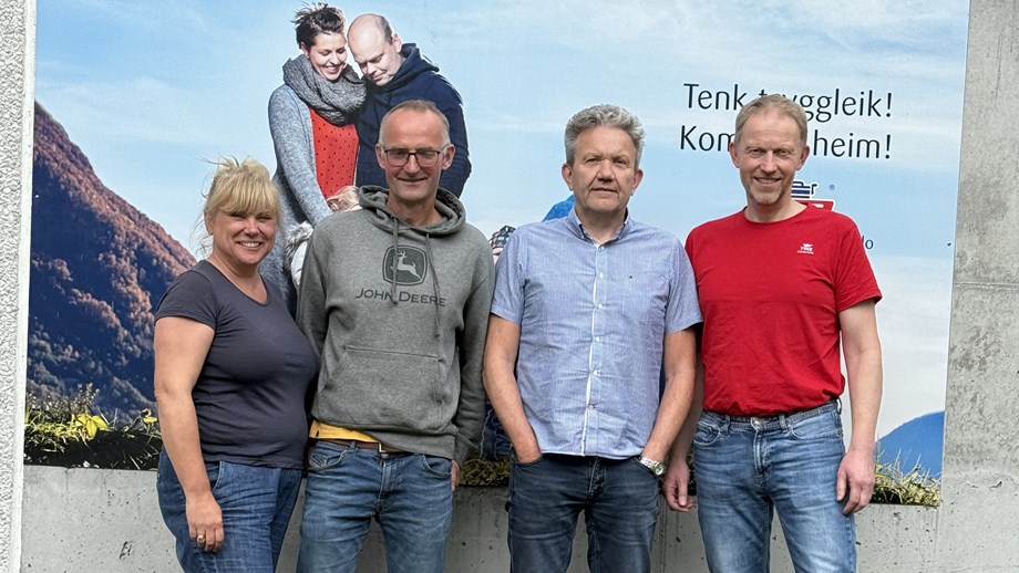 Gjestene og programlederne står oppstilt ute foran en reklameplakat for Tine-melk.